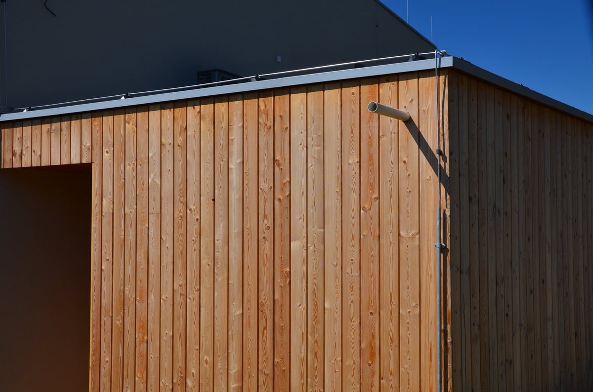 Timber cladding being fitted to a container building with wooden slats over a battened frame