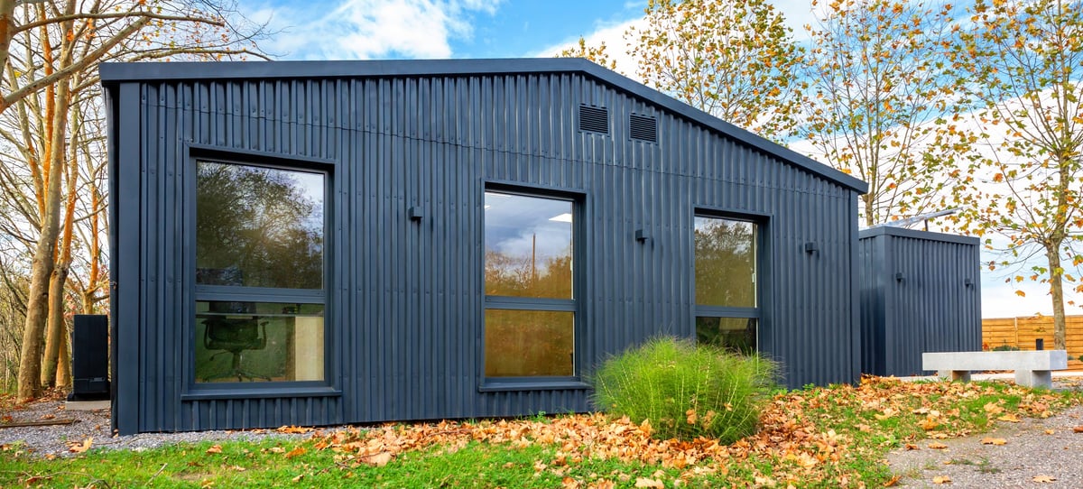 Residence and office building built from shipping containers with dark corrugated steel panels and large windows