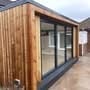 Modern wooden cabin or tiny home with vertical timber siding and large glass windows