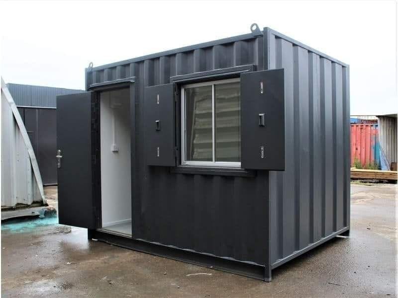 Black corrugated metal shipping container converted into a modern modular office or living space with window